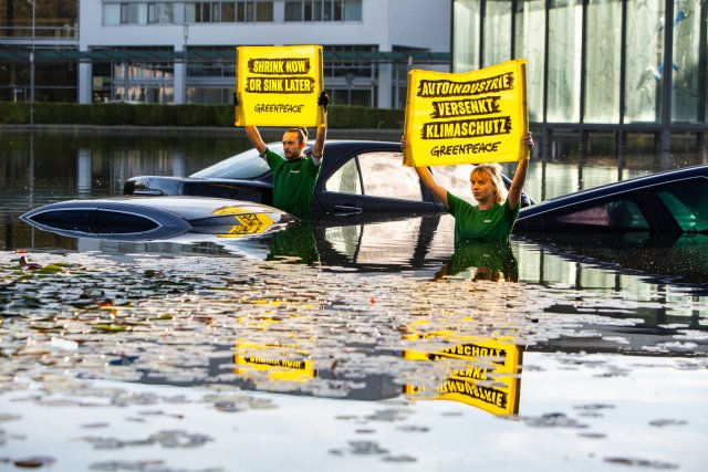 Nasser Protest: Greenpeace-Aktivist*innen demonstrieren mit drei versenkten Autodächern in einem Wasserbecken vor der Messe in München.