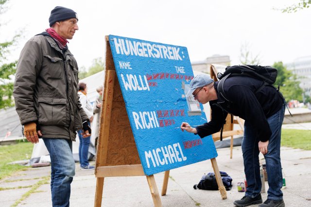 Der Aktivist Adrian Lack macht seinen ersten Strich: Seit dem 7. Mai befindet er sich im Hungerstreik. Für Wolfgang Metzeler-Kick (links im Bild) ist es Tag 62 ohne Essen.
