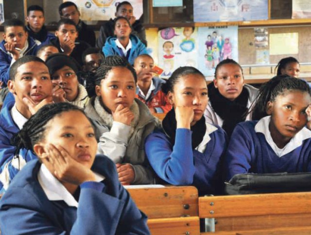 Schülerinnen und Schüler schauen einen Film über fremdenfeindliche Gewalt in Südafrika.