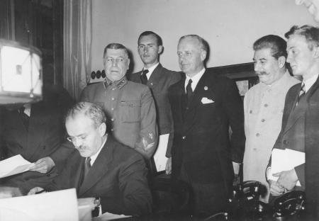 Molotow signiert den Nichtangriffsvertrag, hinter ihm Ribbentrop und Stalin