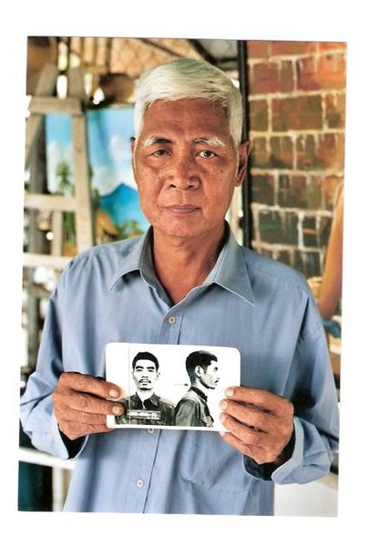 Vann Nath heute mit einem Foto, das ihn als Häftling des Gefängnisses S 21 zeigt