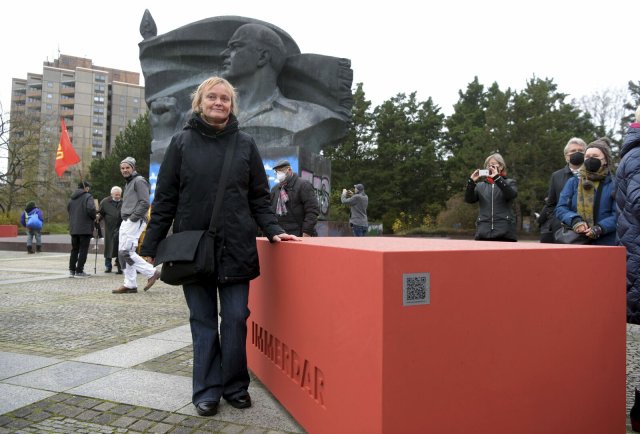 Künstlerin Betina Kuntzsch steht am Thälmann-Denkmal in Berlin. Neben ihr liegt eine der von ihr entworfenen Miniausgaben des Sockels.