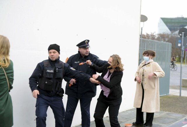 Polizisten hindern Miriam Meyer daran, weitere Parolen ans Kanzleramt zu schreiben, beobachtet von Suse Wißkirchen (rechts)