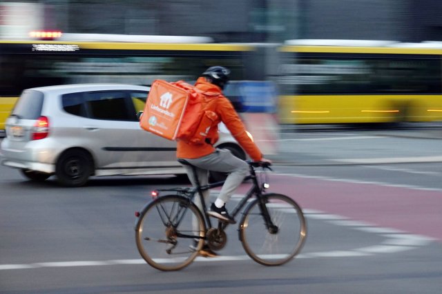 In Neon-Orange gegen den Autoverkehr: Ein Lieferando-Kurier unterwegs in der Hauptstadt