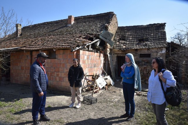 Ramadan Tatari und Tochter Elvira (l.) vor dem zerstörten Haus der Familie im Dorf Debeljaca mit Jelena Micovic (r) von der Belgrader Beratungsstelle für Rückkehrende und einer Kollegin.