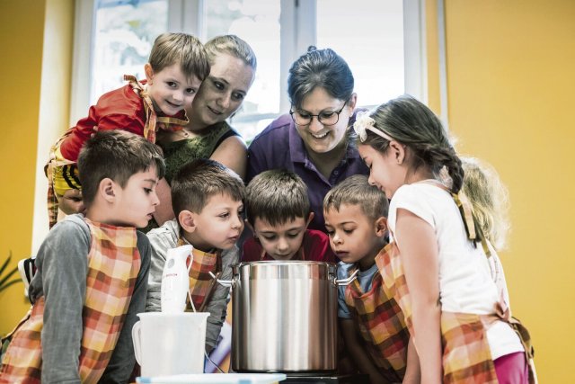 Die Hauswirtschaftsleiterin Hannah Weisshardt (mitte) und die Erzieherin Nicole Stenger kochen mit den Kindern zusammen Apfelmus.
