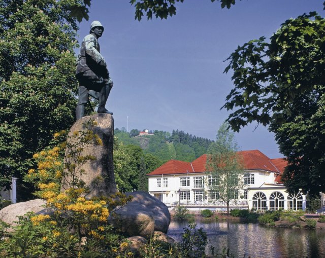 Der bronzene Wissmann in Bad Lauterberg steht dem Kurhaus gegenüber auf einem großen Findling am Ententeich.