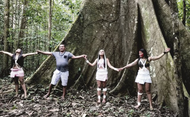 Die Marubo-Familie stellt sich schützend vor einen heiligen Kapokbaum im brasilianischen Regenwald.