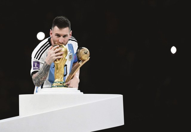 Die Trophäe für den besten Spieler im Arm, einen Kuss für den WM-Pokal: Lionel Messi