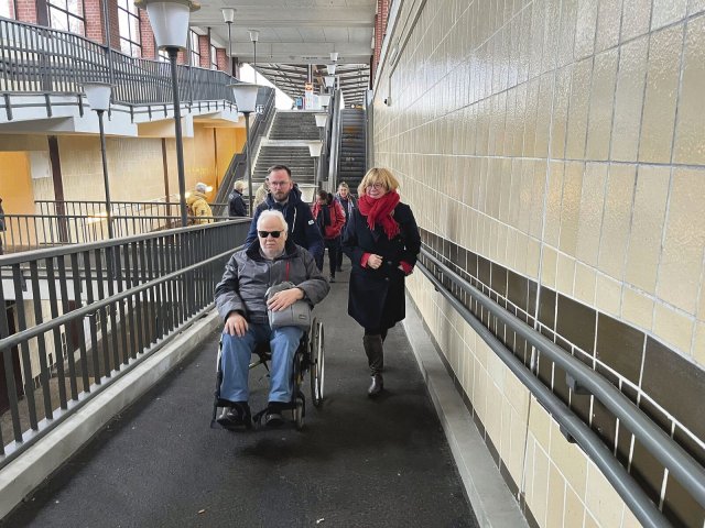 Kristian Ronneburg (Linke) schiebt einen Rollstuhlfahrer die steile Rampe im U-Bahnhof Elsterwerdaer Platz hoch.
