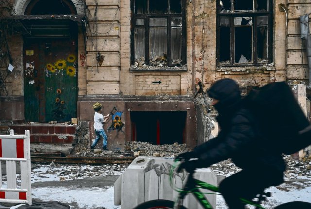 Alltag im zweiten Kriegsjahr: Die Menschen in Kiew verstecken sich nicht. Sie haben sich auf einen länger anhaltenden Krieg eingestellt. Der italienische Street-Art-Künstler TV-Boy bekundet seine Solidarität mit einem Wandbild.
