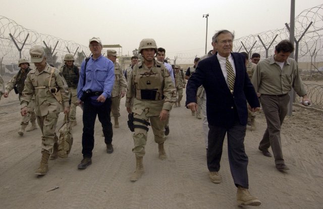 Der ehemalige US-Verteidigungsminister Donald H. Rumsfeld (vorne) bei einem Rundgang 2004 durch das Gefangenenlager Abu Ghraib. Rumsfeld hatte Anweisung gegeben, gefangene »Aufständische« im irakischen Gefängnis Abu Ghraib zu foltern.