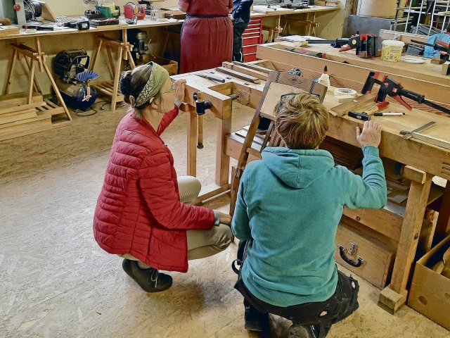 In der Holzwerkstatt im Haus der Materialisierung unterstützen Tischlerinnen bei der Arbeit mit Holzgegenständen, zum Beispiel bei der Reparatur eines rissigen Stuhls.