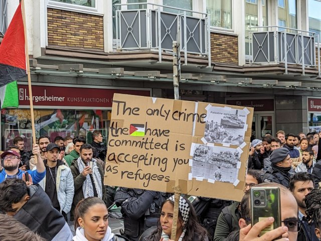 Eine Demonstrantin trägt ein Schild, in dem die Aufnahme von Juden in Palästina als Verbrechen bezeichnet wird.