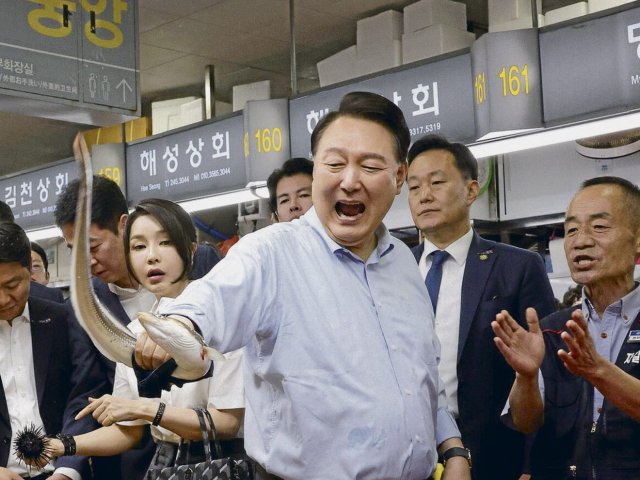 Südkoreas Präsident Yoon Suk-Yeol und ein Aal (links) in der Hafenstadt Busan
