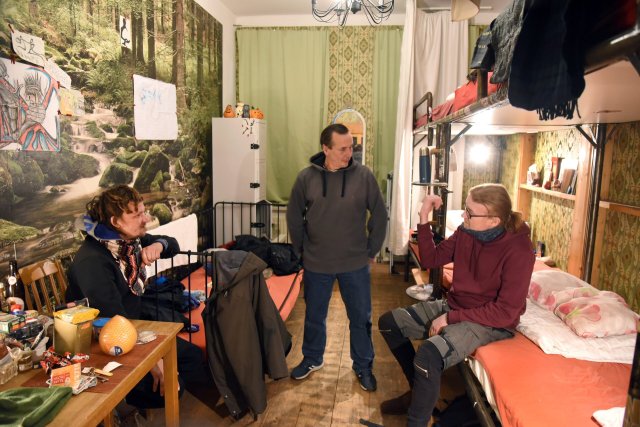 Im Homeplanet-Hostel im Leipziger Stadtteil Connewitz besucht der im vorigen Jahr noch obdachlose 51-jährige Ralf Mertes (M.) den 39-jährigen Michael Schönrock (l.) und den 50-jährigen Wladimir in ihrem Zimmer. Das Hostel stellt eine Etage für wohnungslose Menschen zur Verfügung, kostenlos – mit Frühstück und Abendbrot.