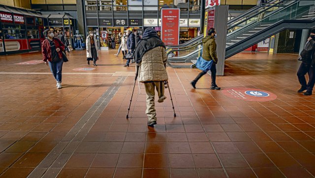 Ein Mann auf Krücken bittet Passanten am Hamburger Hauptbahnhof um Kleingeld.