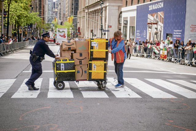 Jederzeit alles an alle zu liefern, ist Knochenarbeit: Ein Paketauslieferer während einer Straßenparade in New York City, April 2023