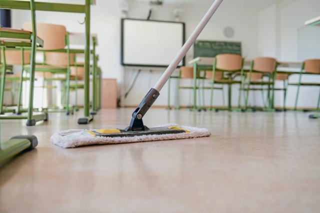 Diese Arbeit ist oft unsichtbar: Eine Reinigungskraft putzt den Boden eines Klassenzimmers.