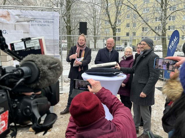 Kai Wegner (CDU) (2.v.l.) lässt sich umringt von Kameras bei der Grundsteinlegung für das Wohnprojekt mit der Rad und Tat Geschäftsführerin Jutta Brambach (3.v.l.) ablichten.