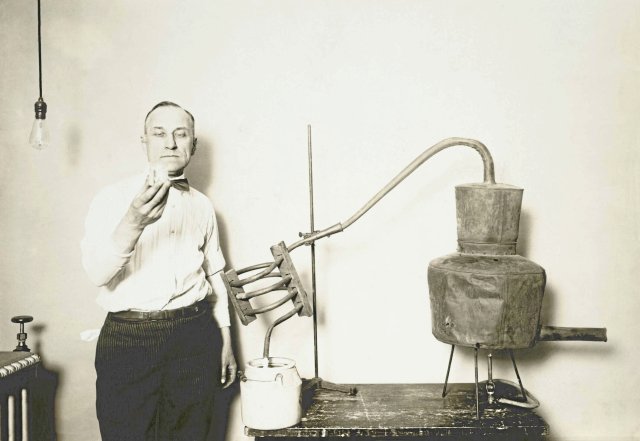 Bronfn im amerikanischen Finanzministerium: Ein Mitarbeiter inspiziert selbstgebrannten Schnaps aus einem zuvor konfiszierten Destillierapparat, Aufnahme circa 1921–32.