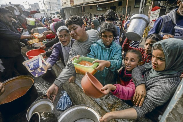Palästinenser stehen in einer behelfsmäßigen Wohltätigkeitsküche in Rafah im südlichen Gazastreifen Schlange, um eine Portion Essen zu erhalten.