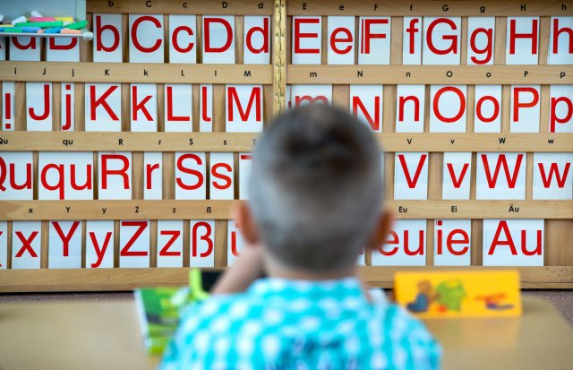 Frontalunterricht: Ein Kind sitzt vor einer Tafel mit Buchstaben...