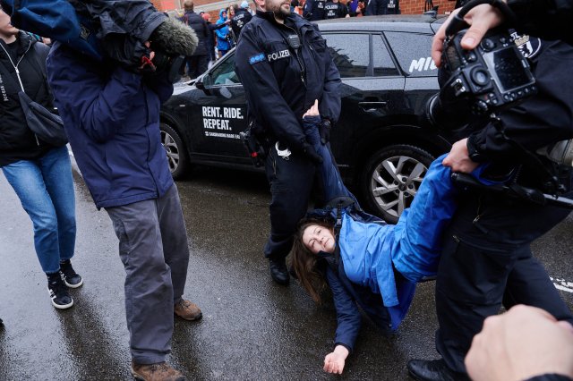 Polizisten ziehen eine Klimaaktivistin von der Straße.
