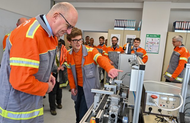Ministerpräsident Dietmar Woidke (SPD) lässt sich in der Lehrwerkstatt des Stahlwerks in Eisenhüttenstadt etwas von dem Auszubildenden Chris Niedlich erklären.
