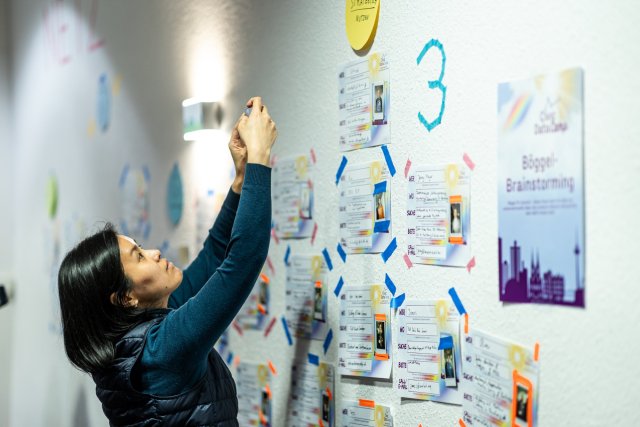 Eine BarCamp-Teilnehmerin vor einer Wand für Kontaktaustausch