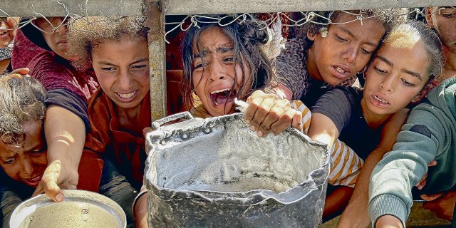 Palästinensische Kinder versuchen im Gebiet Al-Mawasi im Gazastreifen, mit ihren Töpfen Nahrungsmittel zu bekommen, die von Wohltätigkeitsorganisationen verteilt werden.