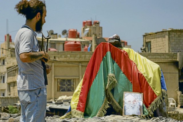 Ein drusischer Kämpfer steht nach dem Waffenstillstand in der Stadt Al-Suweida an einem Kreisverkehr, der mit der drusischen Flagge und einem Porträt eines lokalen Führers geschmückt ist.