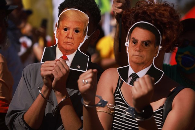 Zwei linke Demonstranten mit Masken von Trump und Bolsonaro habe...
