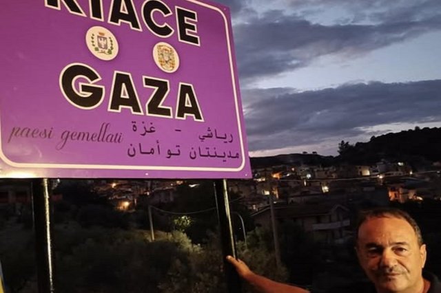 Mimmo Lucano vor einem neuen Schild am Ortseingang von Riace.
