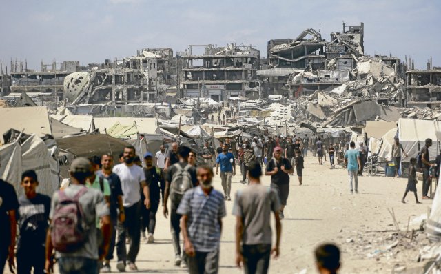 Palästinenser gehen in Gaza-Stadt eine Straße entlang, die von k...
