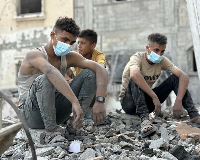 Palästinenser sitzen nach israelischen Angriffen auf den Trümmern zerstörter Gebäude (18. Juli 2025).