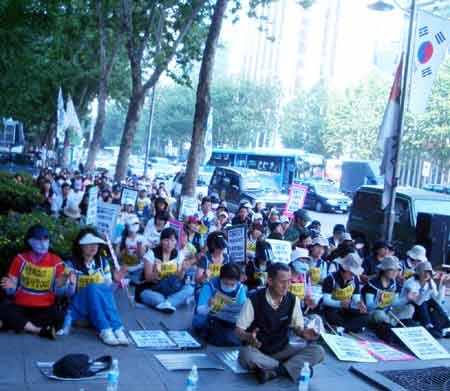 Streikende E-Land-Beschäftigte blockieren den Bürgersteig vor einem Supermarkt (links); »Wir unterstützen den Kampf der Reinigungsfrauen«, steht   oben auf dem Plakat.