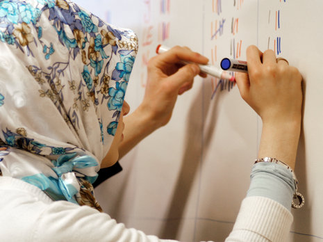 Eine muslimische Sch&#252;lerin schreibt im Englischunterricht an der Tafel. epd/J&#246;rg Stipke