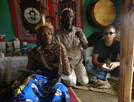 Der Sangoma – der traditionelle Heiler – empfängt in seinem Haus einen Touristen mit dem Reiseführer