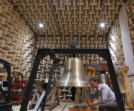 Michael Plitzner untersucht im Schalllabor eine Kirchenglocke mit einer Lupe