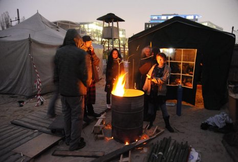 Um die Feuertonne auf dem Occupy-Camp stehen die beiden Camp-Bewohnerinnen Pippa (rechts) und Suna (mitte).